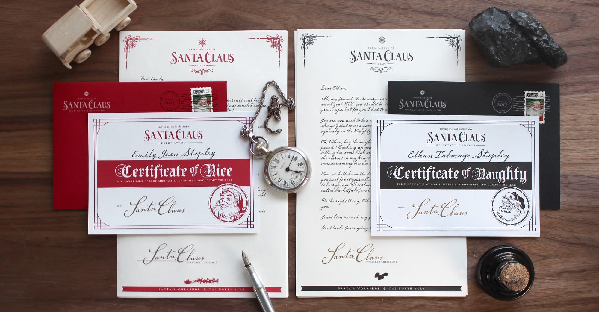 Santa's Red Letter product system flat-lay: a Red Letter set with Certificate of Nice, a Black Letter set with Certificate of Naughty, vintage props including a pocket watch and wooden toy on a wood surface.